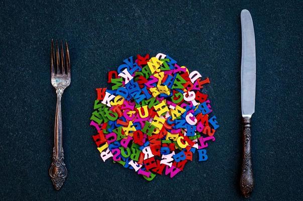 muitas letras de madeira do alfabeto inglês entre o garfo e a faca
